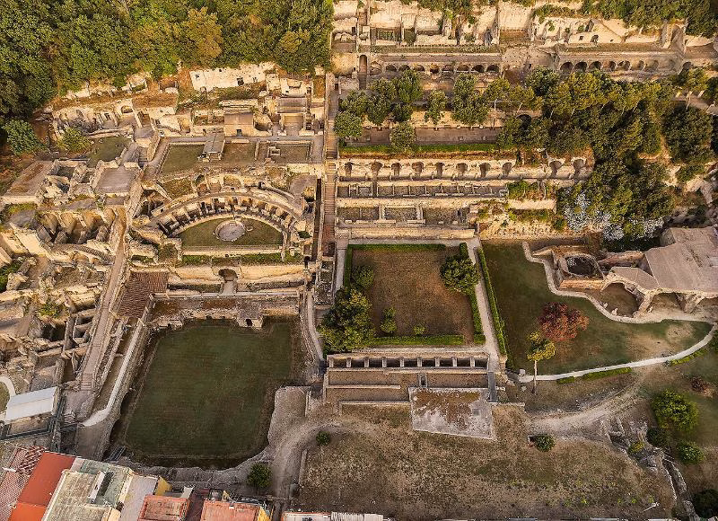 Aerial view of the Archaeological Park of Baia near Naples, showing ancient Roman thermal baths and ruins surrounded by greenery.
