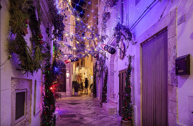 Christmas decorations and lights illuminating a narrow stone alley in Locorotondo’s historic centre in winter.