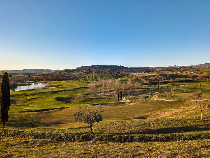 Panoramic view of Terme di Saturnia golf course with rolling fairways, water features and Tuscan hills at sunset