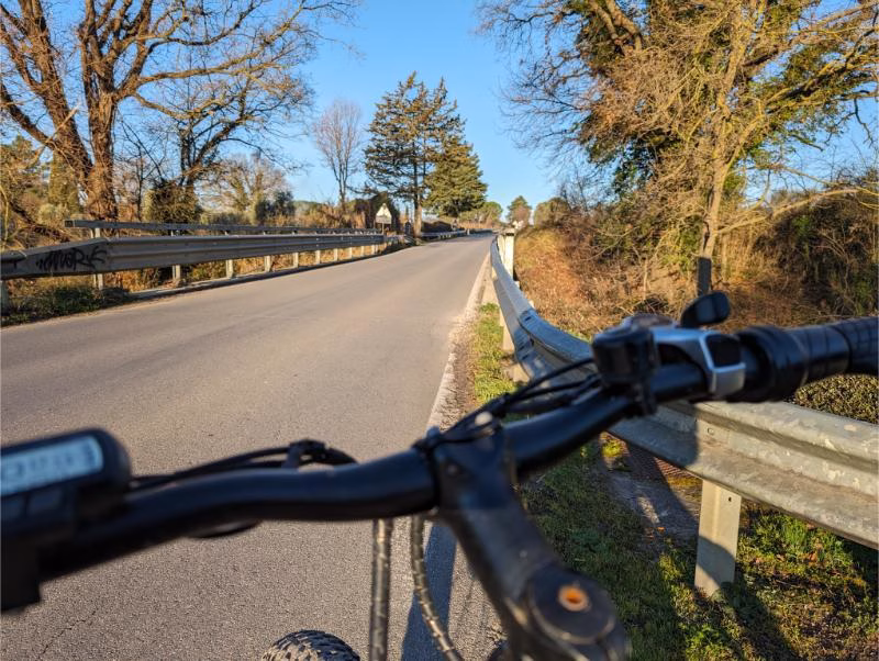 View along a quiet country road near Saturnia framed by the handlebars of an e-bike