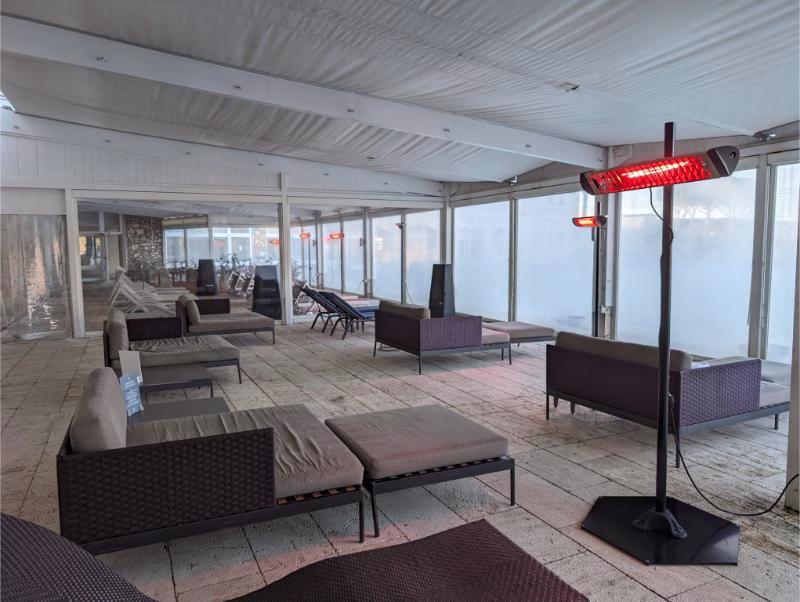 Covered relaxation lounge at Terme di Saturnia with sofas, loungers and infrared heaters beside the steaming pools