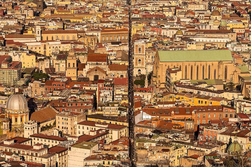 Aerial view of Spaccanapoli slicing the Centro Storico east–west, with Santa Chiara’s long roof and dense palazzi on either side.
