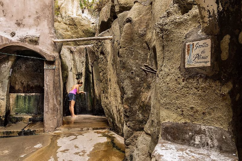 Bather under natural thermal shower in Grotta di Plinio, Cavascura.