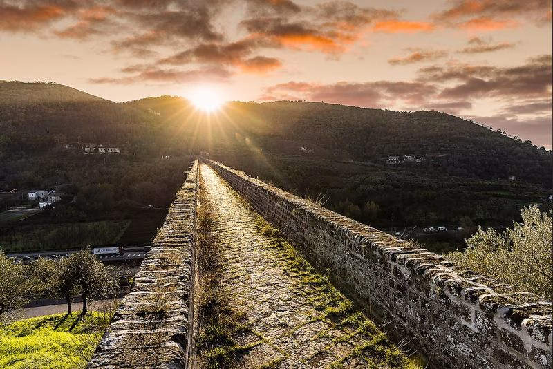 Carolino Aqueduct at sunrise with golden light across the ancient stone path.