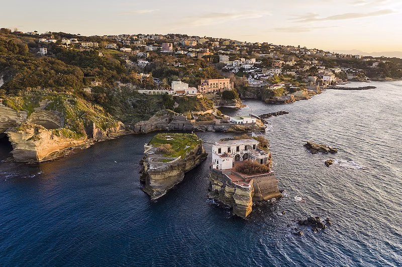 Aerial view of the twin islets of Gaiola off Posillipo, linked by a stone arch, with caves and the rocky coast of the marine reserve.