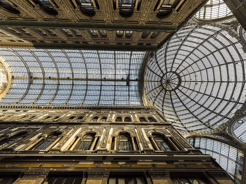 Glass dome and iron vaults of Galleria Umberto I seen from the arcade floor—Naples’ late-19th-century promenade.