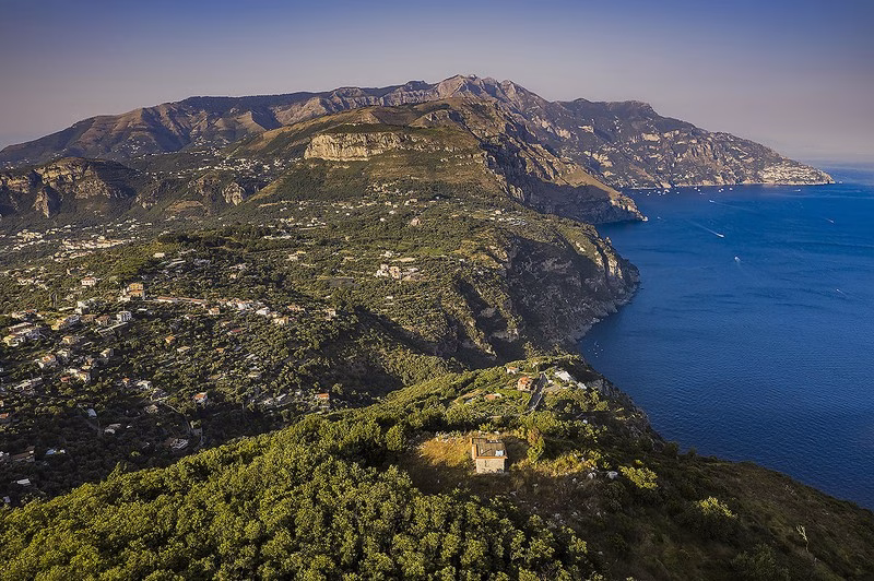 Aerial view of Massa Lubrense coastline with the Amalfi Coast cliffs in the distance.