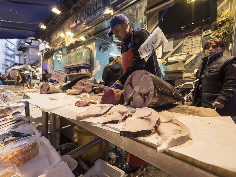 Fresh Fish Stall in Naples Market Fishmonger cutting swordfish at a Naples market stall.