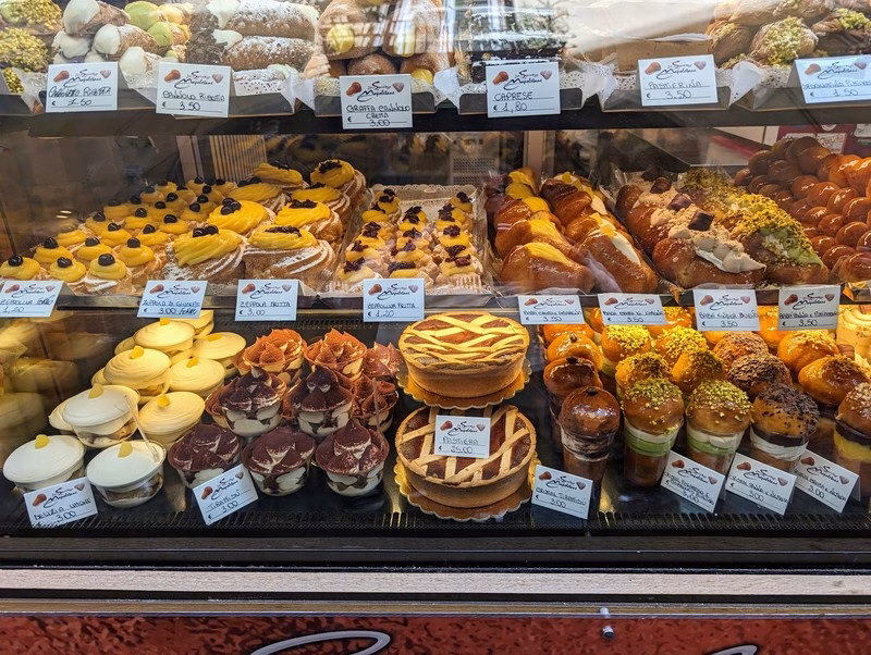 Neapolitan Pastries in Naples Display of traditional Neapolitan pastries including babà, pastiera, zeppole, and delizia al limone.