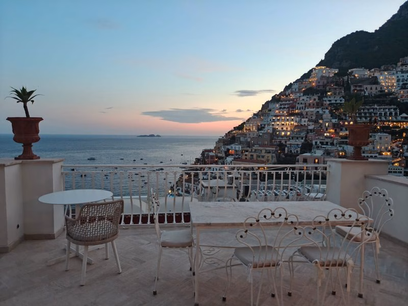 Villa Rosa Positano — terrace view at dusk over the bay and village lights