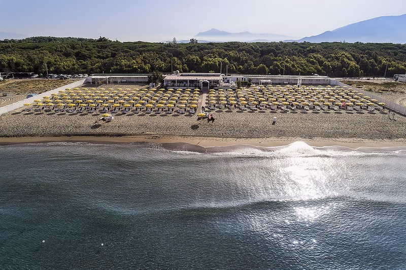 Aerial view of Paestum Beach with rows of yellow umbrellas and calm blue waters along the Cilento coast