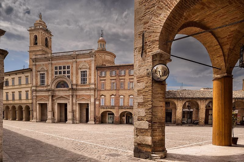 Piazza del Popolo in Offida, Le Marche, with the main church façade and stone-and-brick arcades framing the square