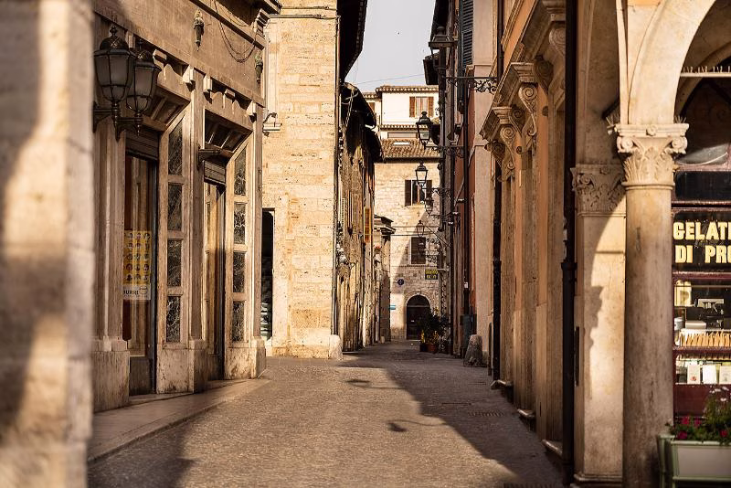 Quiet lane in Ascoli Piceno’s historic centre with travertine façades, arcades and soft morning light
