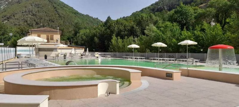 Outdoor thermal pools at Terme di Frasassi, surrounded by wooded hills in the Esino Valley, Marche