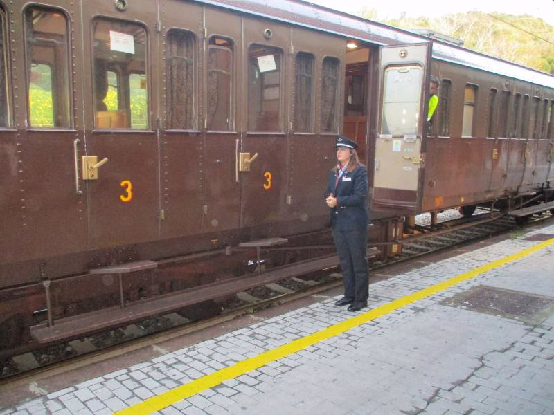 Historic Italian train carriage with railway staff on platform