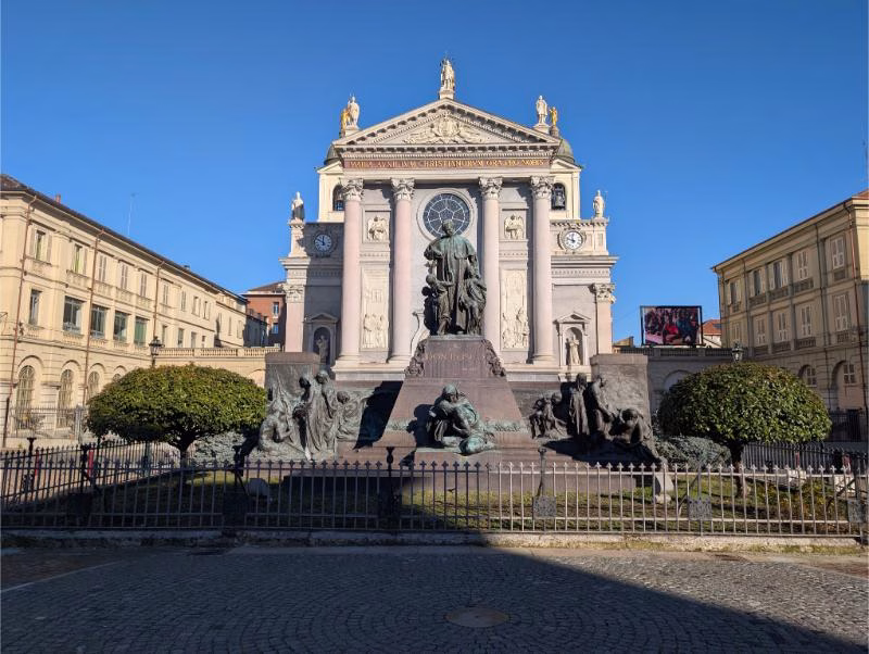 Monument to Don Bosco in front of the Basilica of Maria Ausiliatrice, Turin, with sculptural groups representing youth, care, and education.