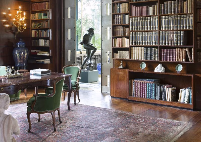 Villa Necchi Campiglio library with built-in bookcases, desk and sculpture near the garden doors