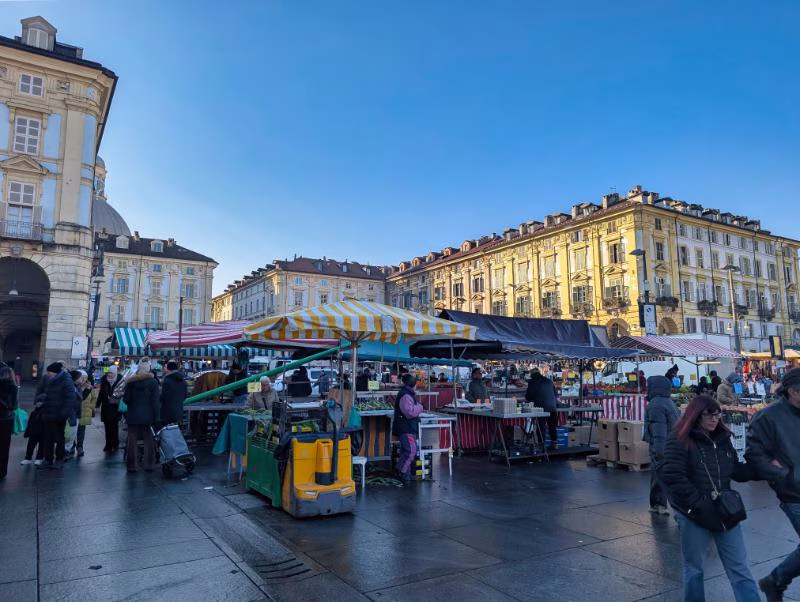 Porta Palazzo market stalls in Piazza della Repubblica with striped awnings and Turin’s arcaded façades