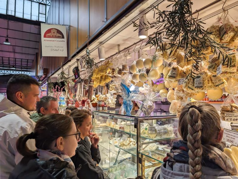 Deli stall at Porta Palazzo with hanging pasta, cheeses and cured meats above the counter