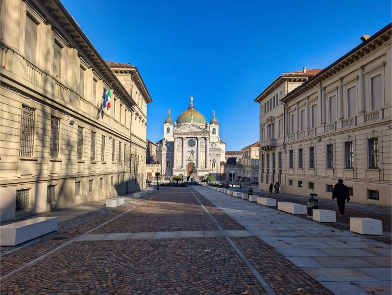 Basilica of Maria Ausiliatrice in Turin’s Aurora district, viewed along the axial pedestrian approach between historic institutional buildings.