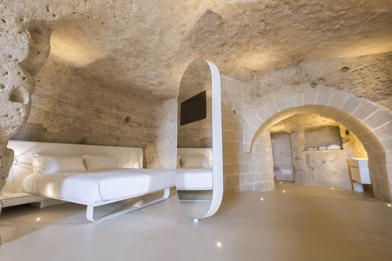 Design-led cave suite at Aquatio Cave Luxury Hotel in Matera with minimal furnishings and carved limestone architecture.