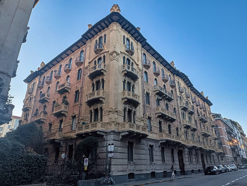 Liberty residential block with corner articulation, Turin Early 20th-century Liberty apartment building in Turin with chamfered corner, brick façade, stone articulation and repeated balconies