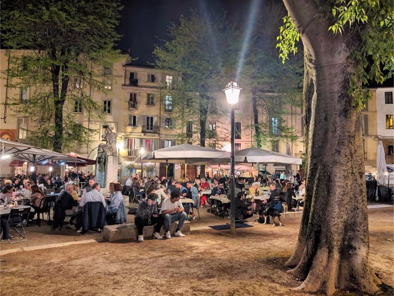 Evening life in Piazza IV Marzo in Turin, with cafés and people gathering in the Quadrilatero Romano.
