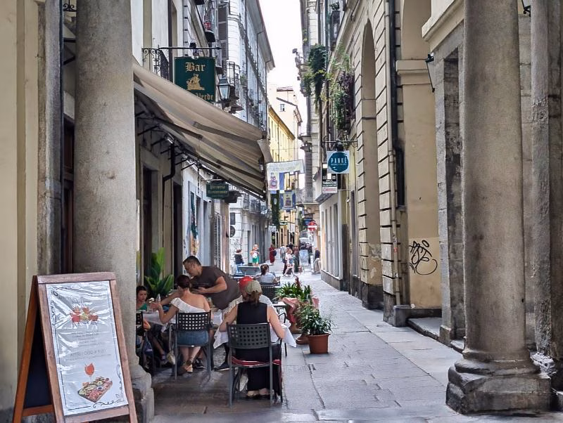 Narrow street with porticoes and outdoor seating in the Quadrilatero Romano, Turin.