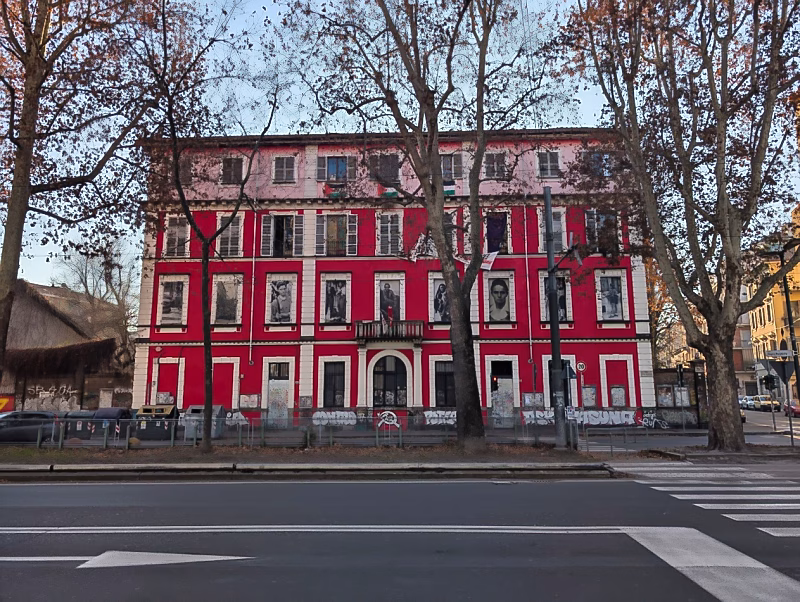 Red building with murals and posters along Corso Regina Margherita in Vanchiglia, Turin