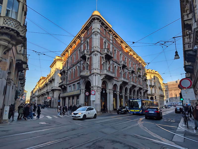 Late-19th-century corner palazzo in western Turin with porticoes, arched ground floor, and iron balconies along a major street intersection.