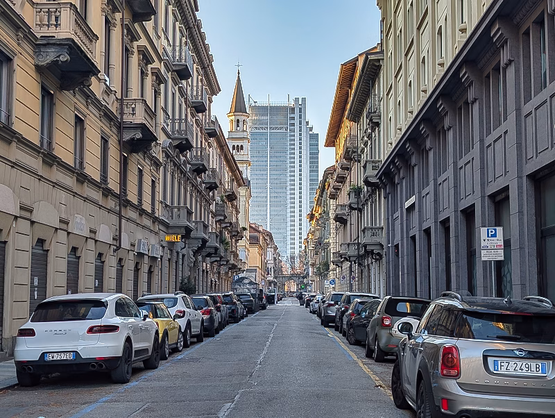 Straight residential street in western Turin lined with late-19th-century apartment buildings and continuous façades.