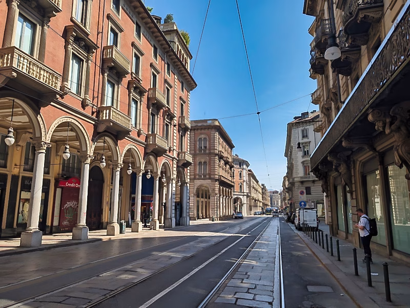 Via Pietro Micca in Turin, showing tram tracks, porticoes, and late-19th-century residential palazzi along a broad diagonal street.