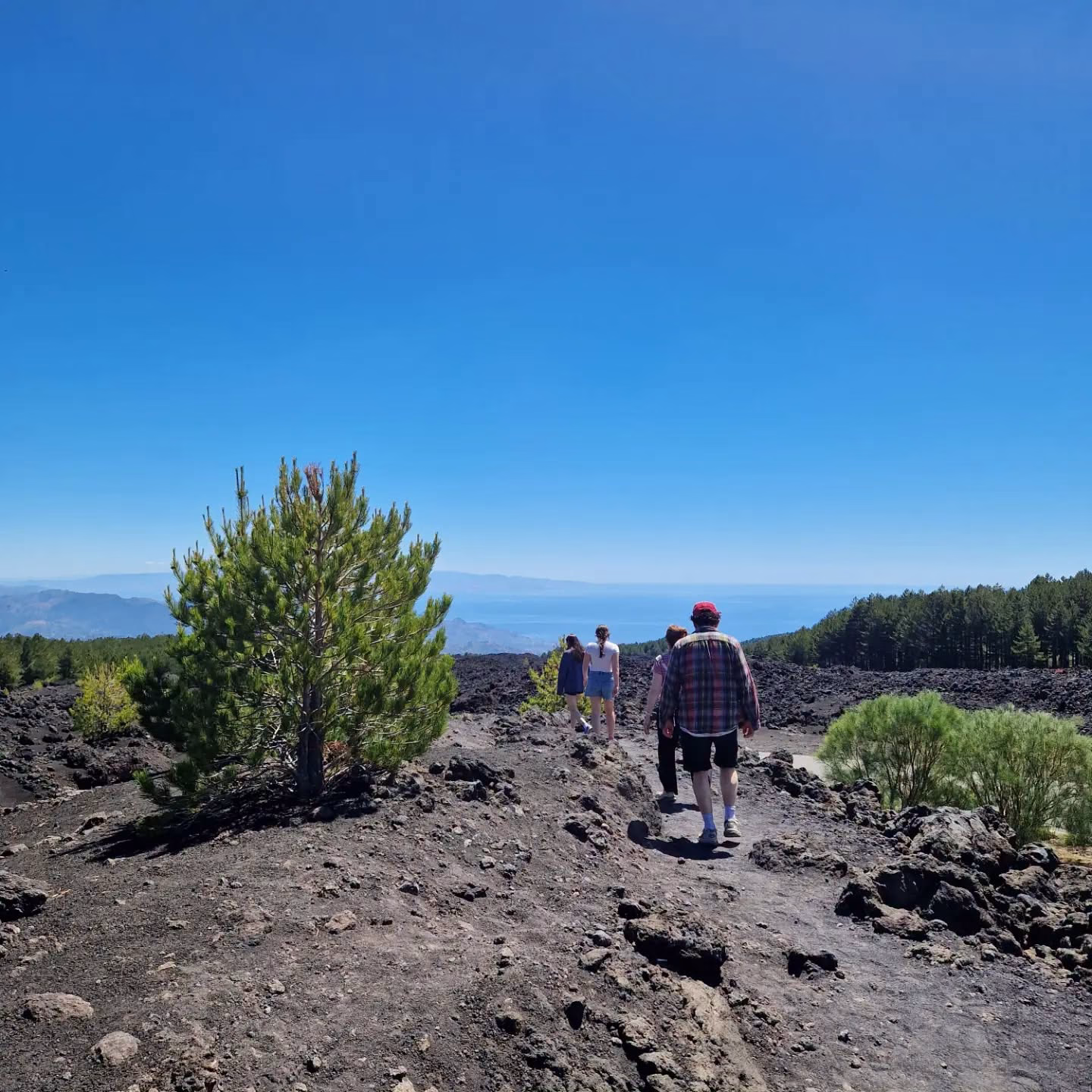 Travellers walking with Giusi across Mount Etna’s volcanic landscape