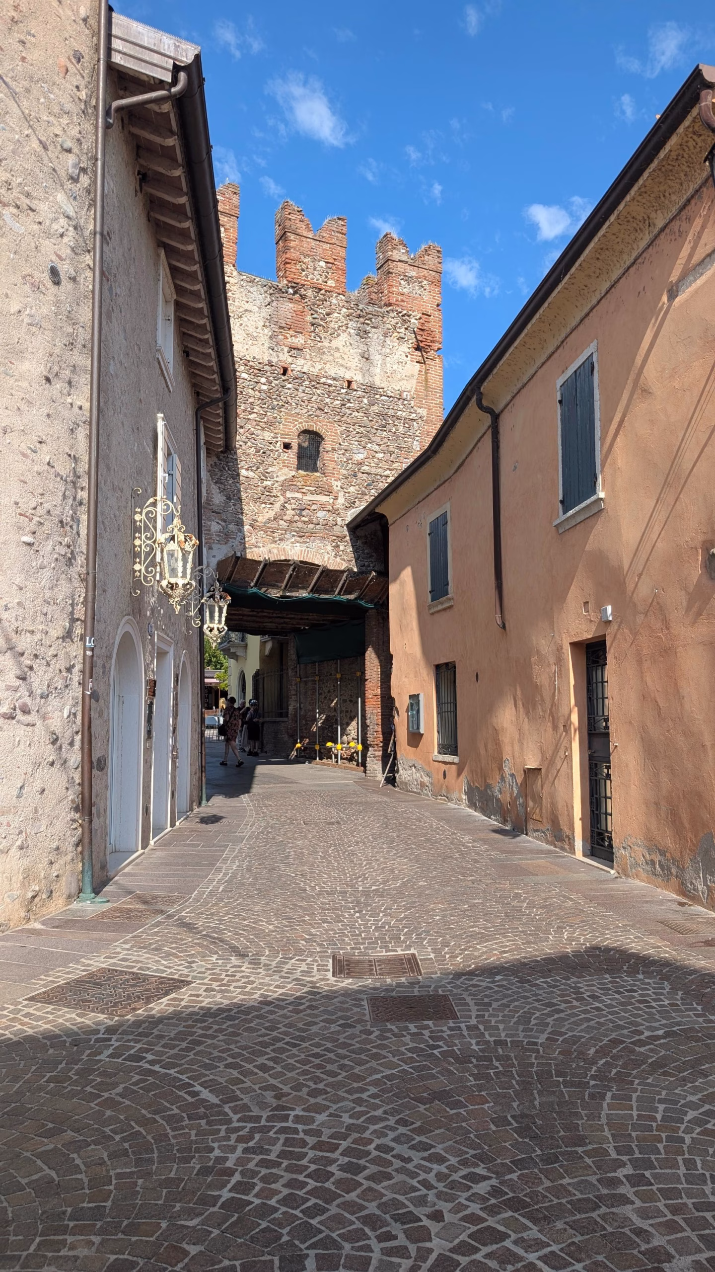 Narrow lane between houses leading towards a medieval tower in Borghetto