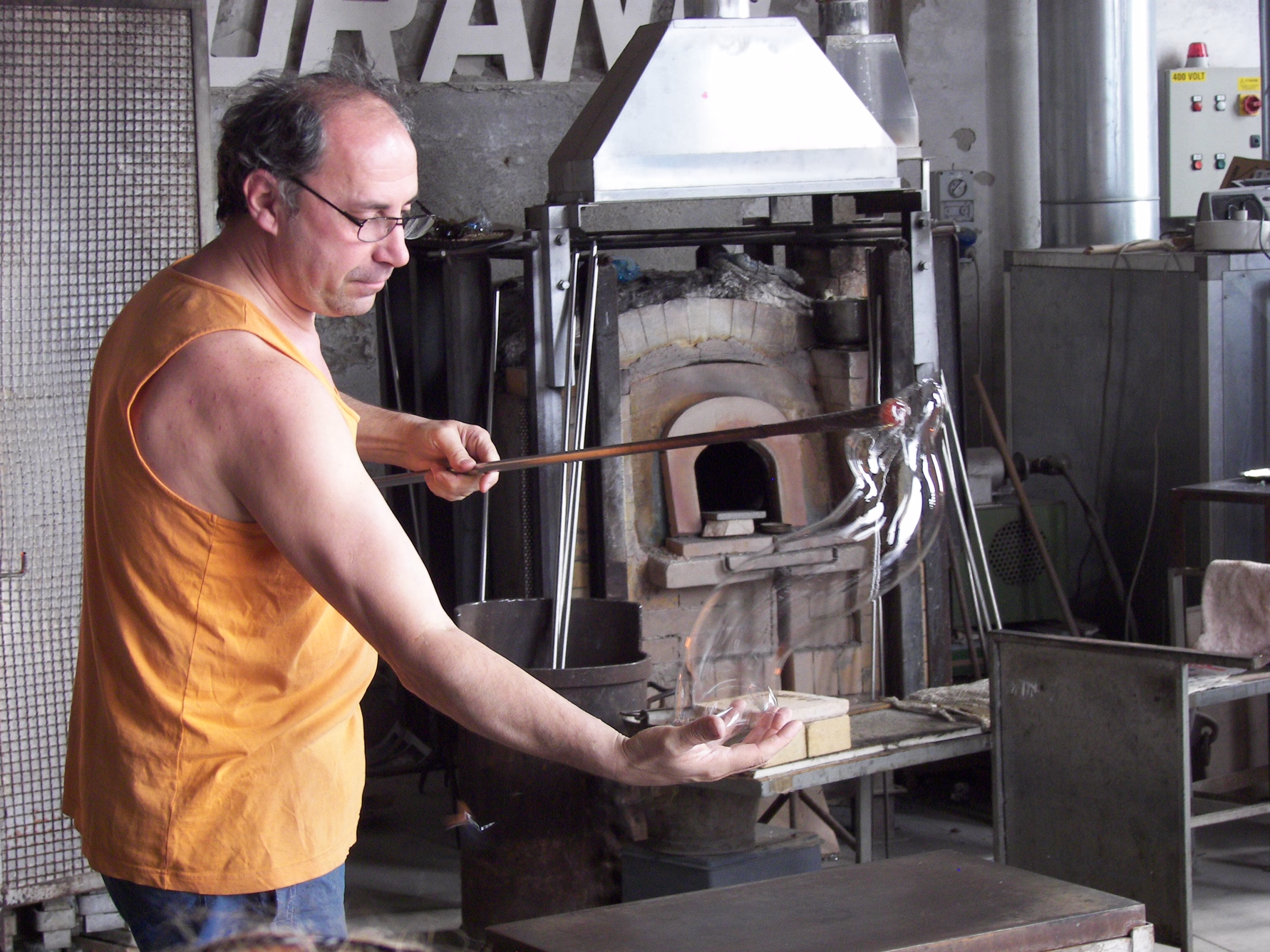 A Murano glassmaker shapes a clear glass horse beside a furnace