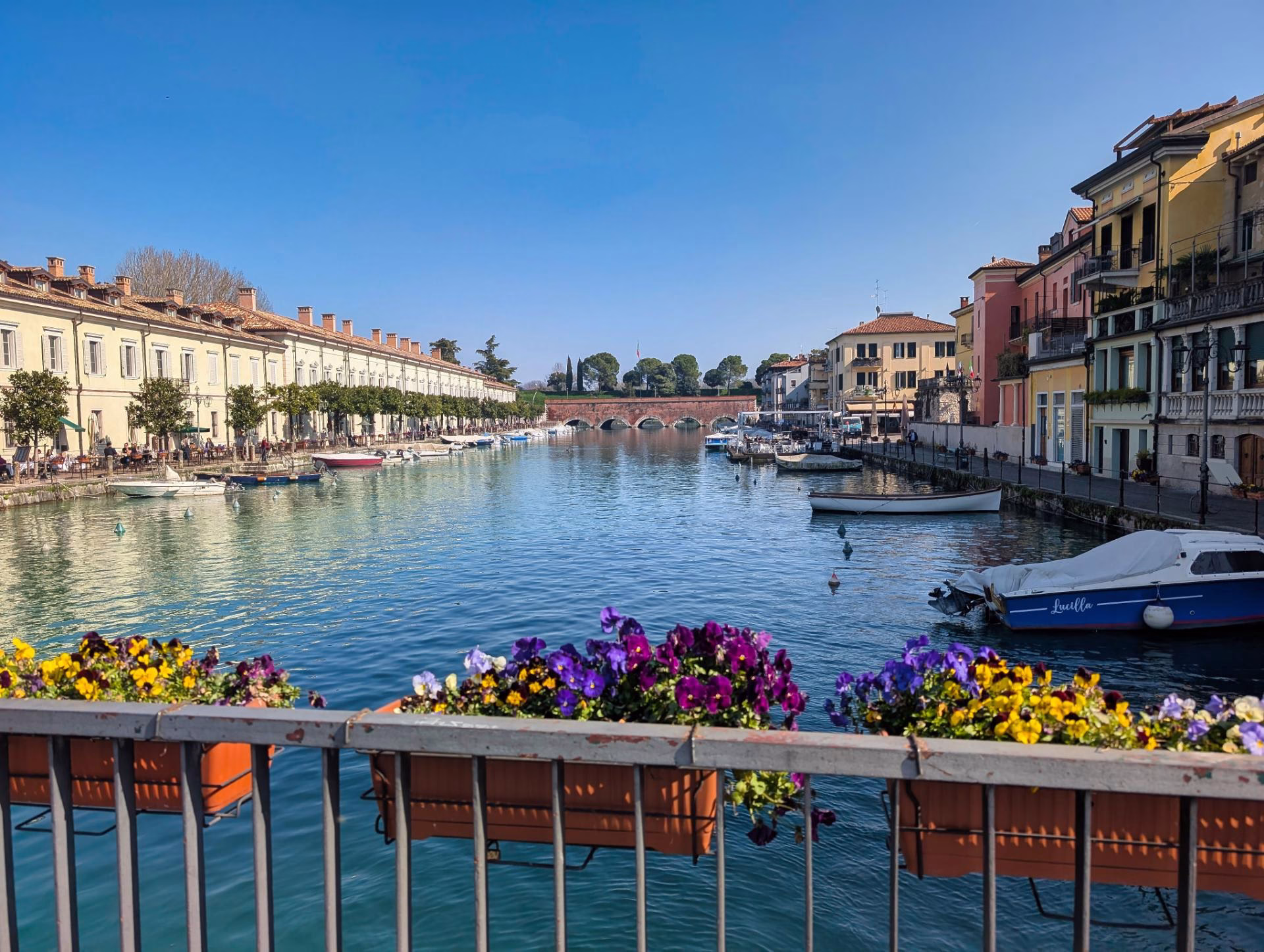 Boats and waterfront buildings reflected in a canal at Peschiera del Garda