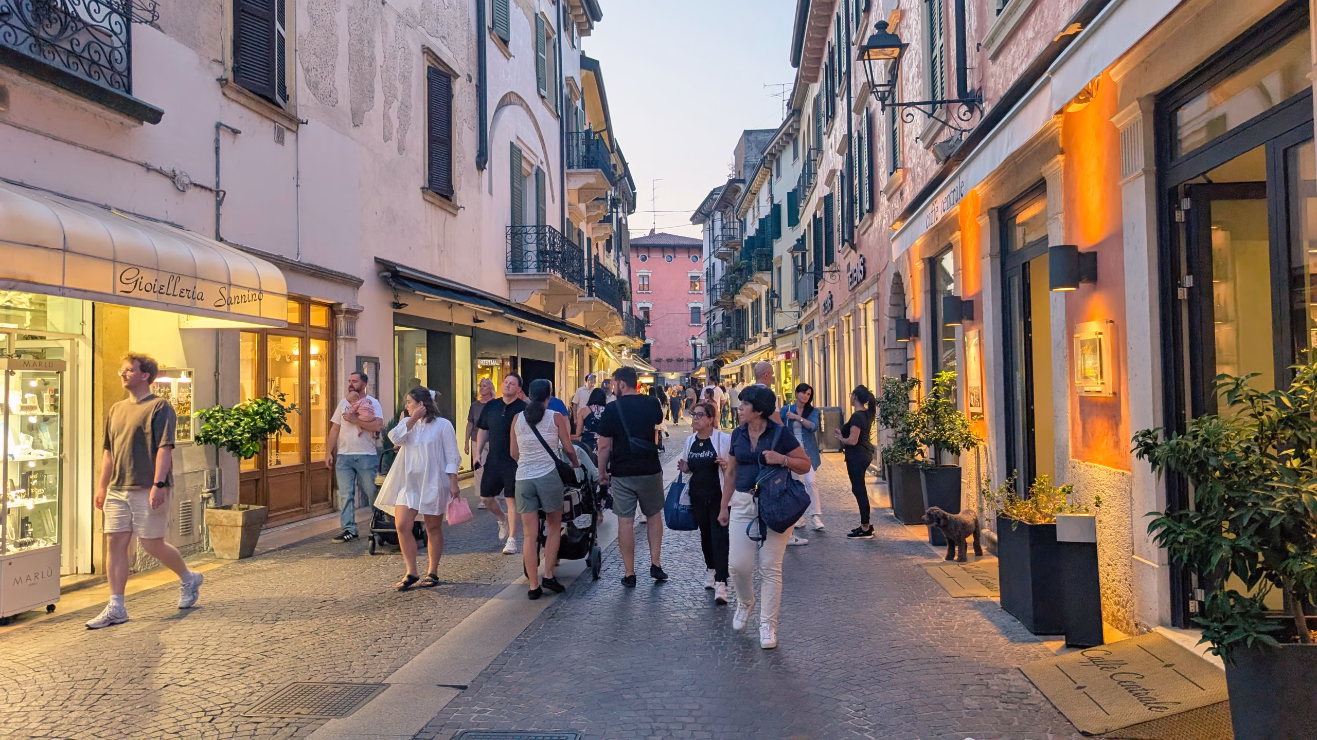 People walking between shops along a narrow street in Peschiera del Garda